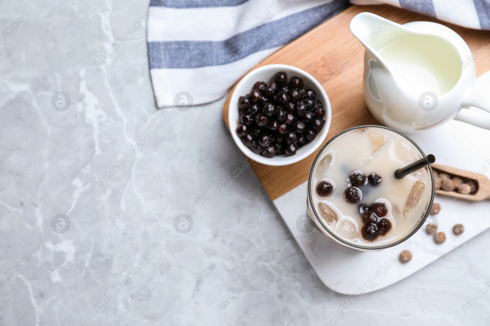 Photo of Bubble milk tea with tapioca balls on light grey marble table, flat lay. Space for text