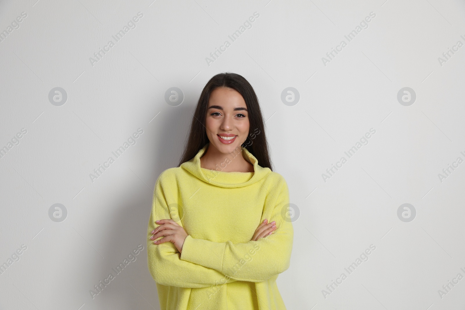 Photo of Beautiful young woman wearing yellow warm sweater on white background