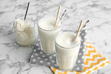 Glasses with milk shake and tasty vanilla ice cream on light background