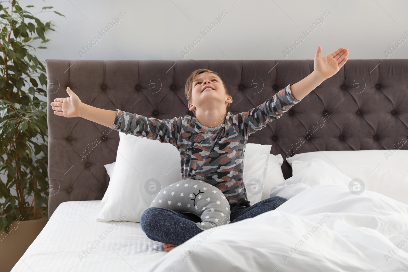 Photo of Cute boy with toy stretching after sleep on bed