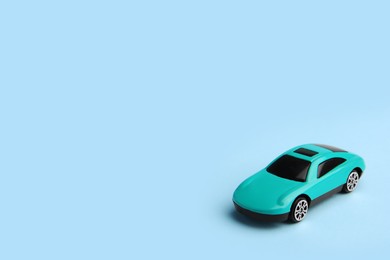 Photo of One bright car on light blue background, space for text. Children`s toy