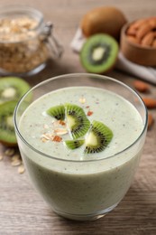 Photo of Glass of tasty kiwi smoothie with oatmeal on wooden table, closeup