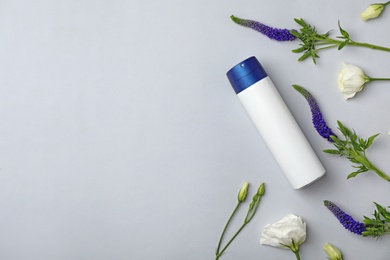 Photo of Deodorant and flowers on light background, top view