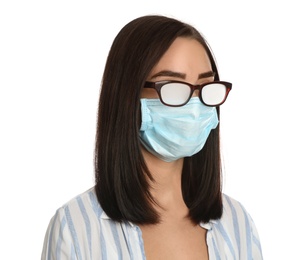 Young woman with foggy glasses caused by wearing disposable mask on white background. Protective measure during coronavirus pandemic