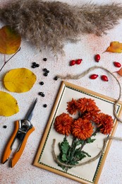 Photo of Flat lay composition with secateurs, twine and Chrysanthemum flowers on light textured table