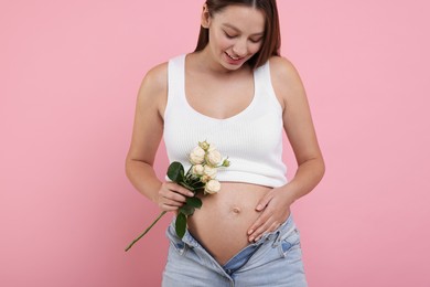 Beautiful pregnant woman with roses on pink background