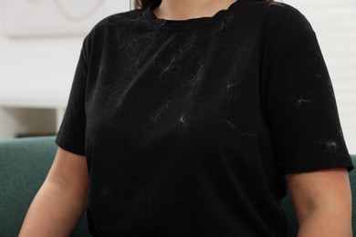 Photo of Woman with pet hair on her black clothers indoors, closeup