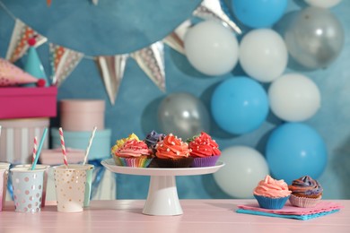 Different colorful cupcakes and party accessories on pink table