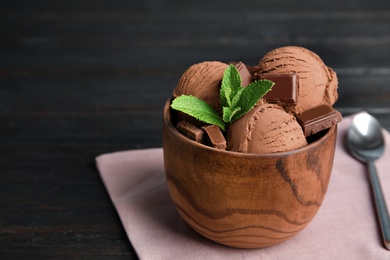 Photo of Wooden bowl of chocolate ice cream and mint on dark table, space for text