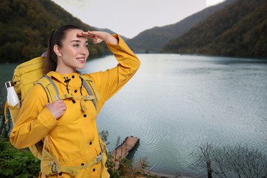 Tourist with backpack near lake between hills