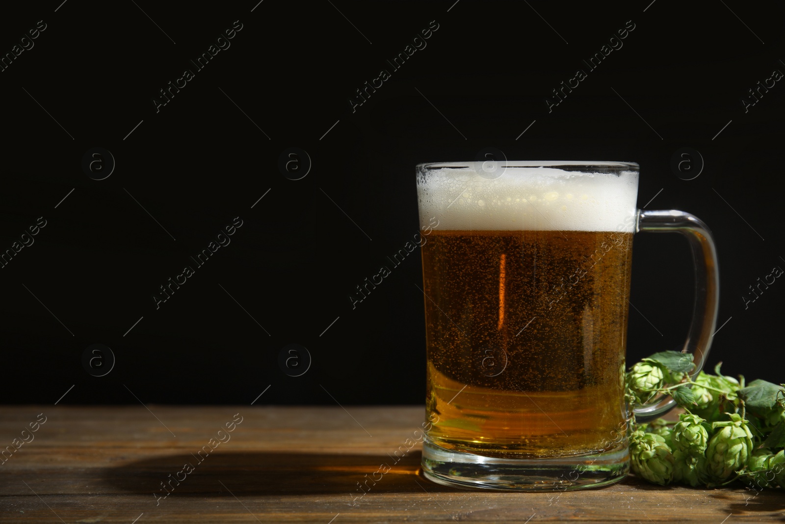 Photo of Composition with tasty beer and fresh green hops on wooden table. Space for text