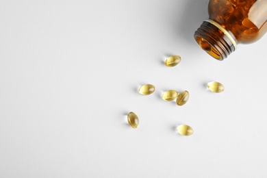 Photo of Bottle with cod liver oil pills and space for text on light background, flat lay