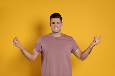 Handsome man snapping fingers on yellow background