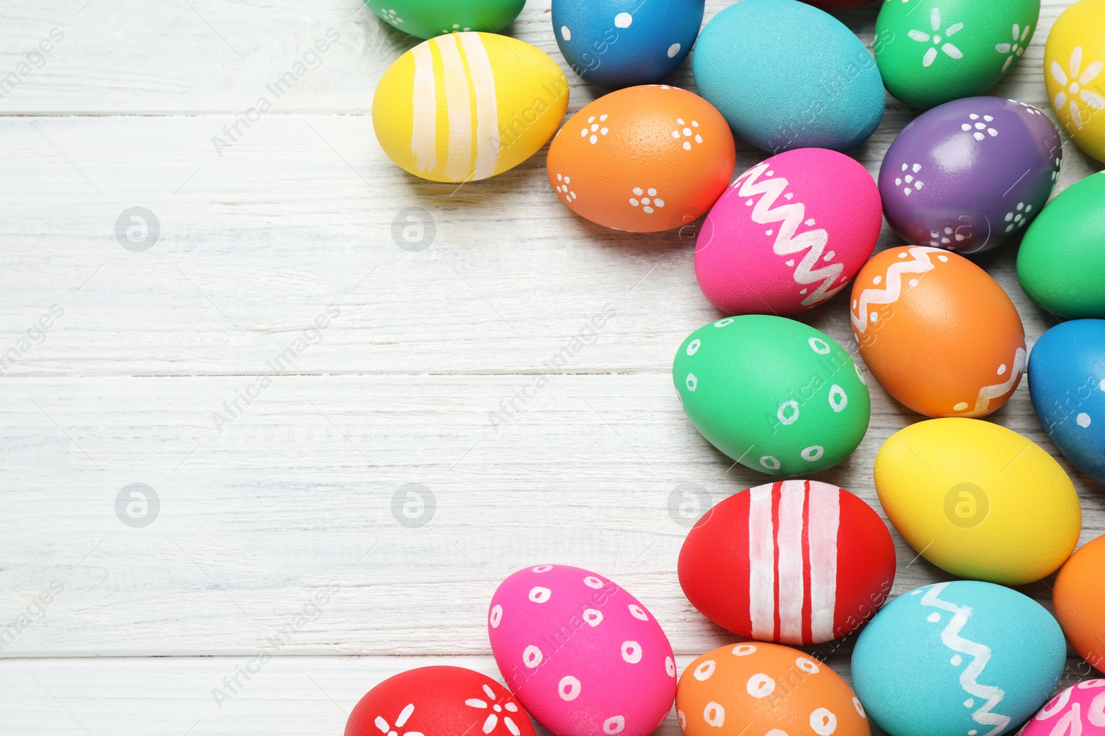 Photo of Many bright Easter eggs on white wooden background, flat lay. Space for text