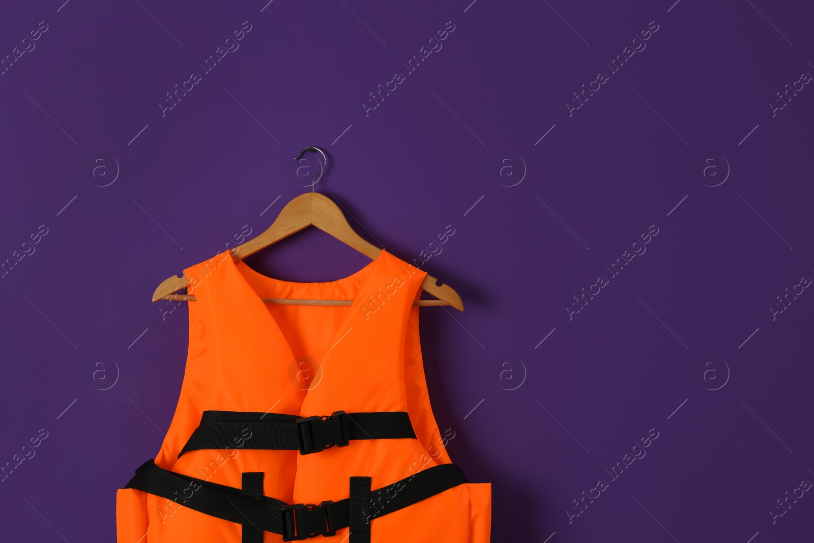 Photo of Orange life jacket on violet background. Space for text