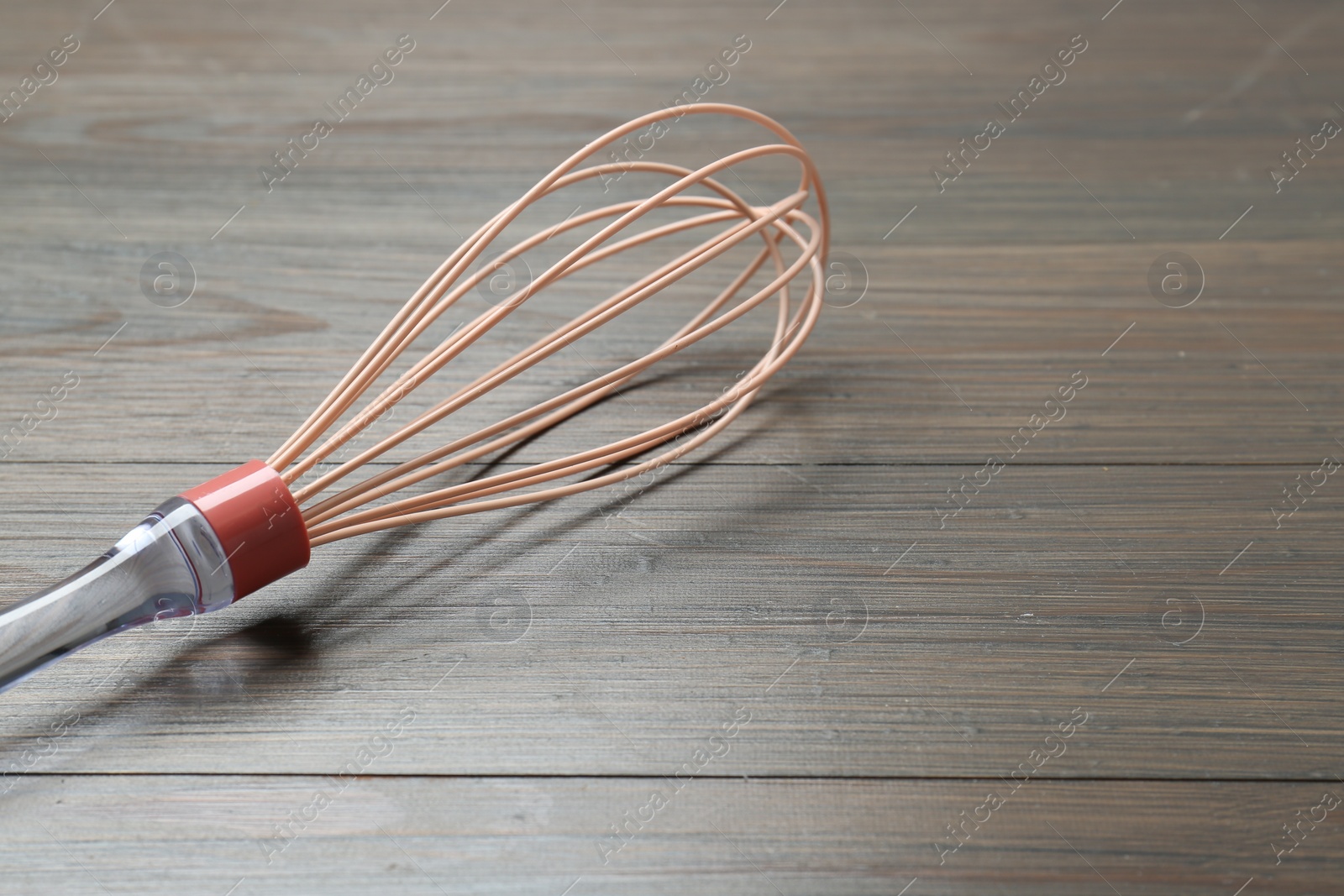 Photo of One whisk on wooden table, closeup. Space for text