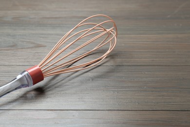 One whisk on wooden table, closeup. Space for text