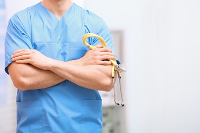 Medical assistant with stethoscope in hospital, closeup. Space for text