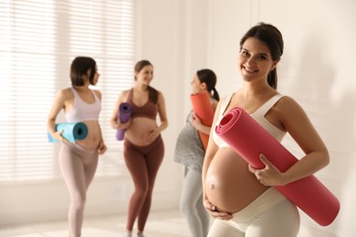 Photo of Group of pregnant women with mats in yoga class, space for text