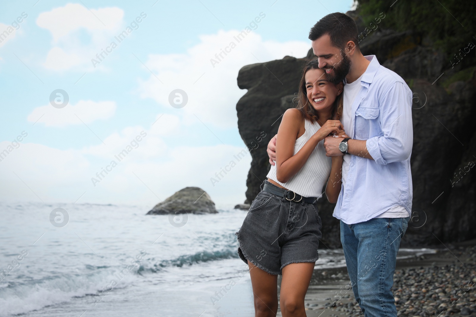 Photo of Happy young couple on beach near sea. Space for text