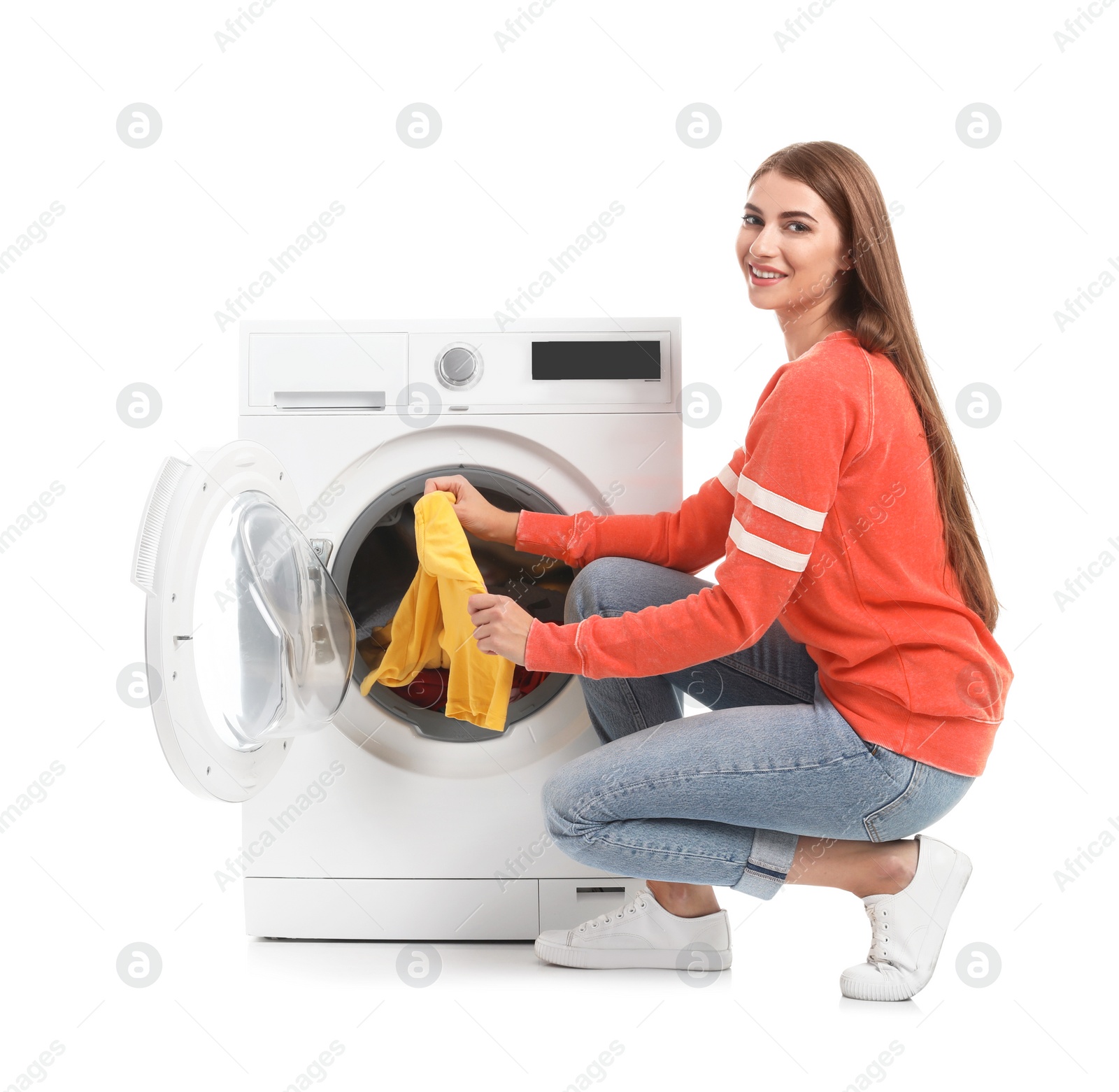 Photo of Young woman taking laundry out of washing machine on white background