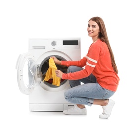 Young woman taking laundry out of washing machine on white background