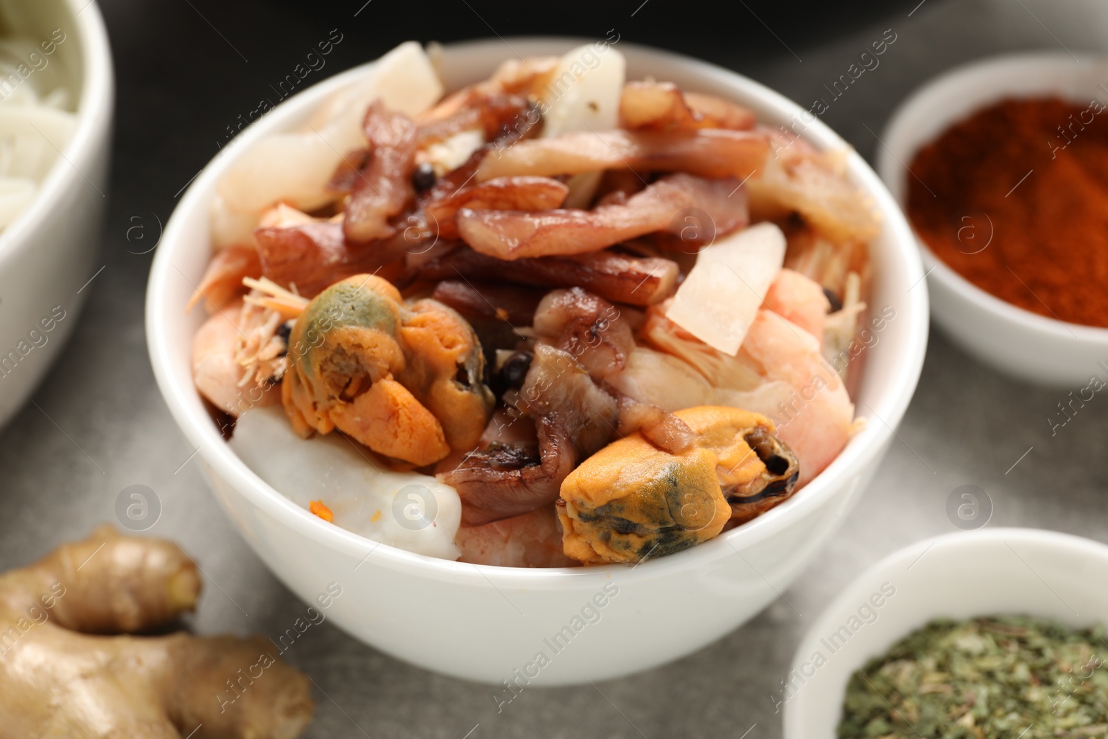 Photo of Seafood and spices for cooking wok on grey table, closeup