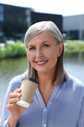 Photo of Portrait of happy senior woman with paper cup of coffee outdoors