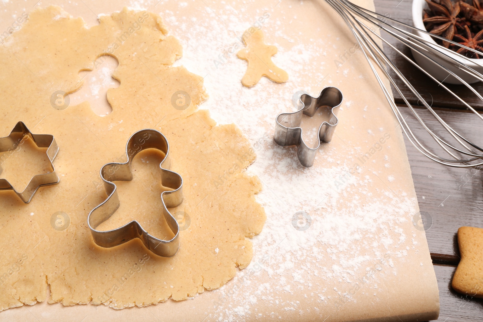 Photo of Making Christmas cookies. Raw dough, whisk and cutters of different shapes on wooden table