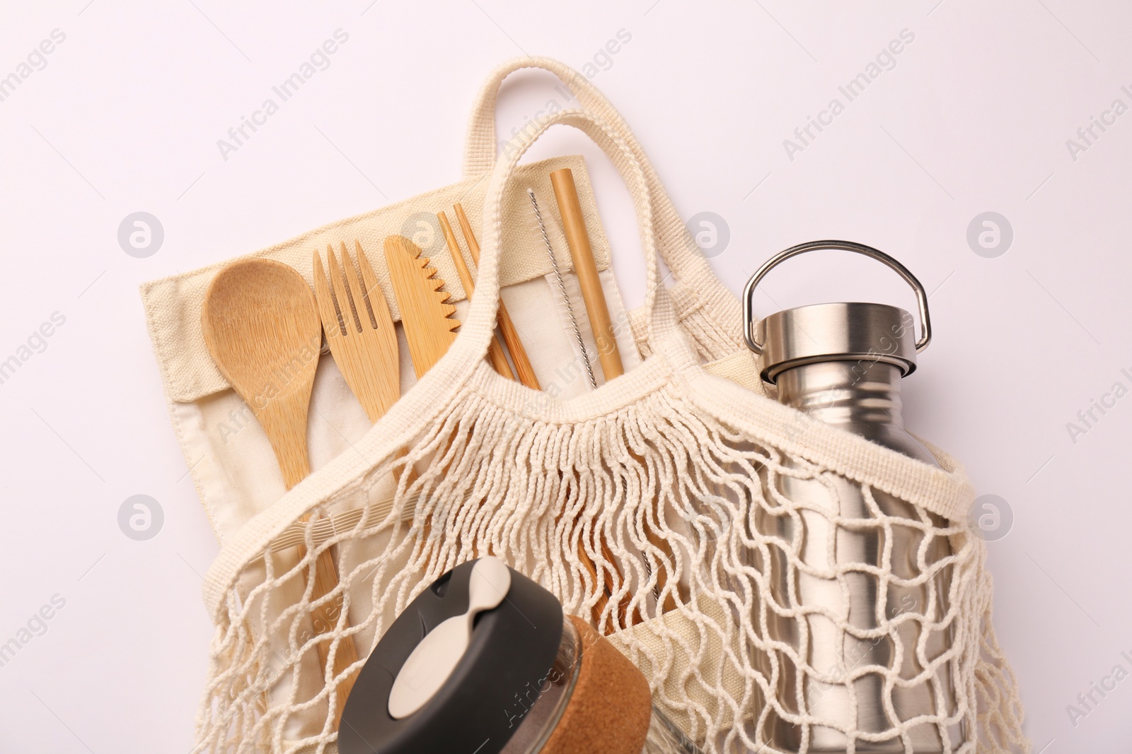 Photo of Fishnet bag with different items on white background, top view. Conscious consumption