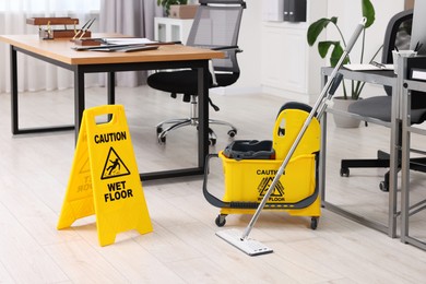 Cleaning service. Mop, wet floor sign and bucket in office