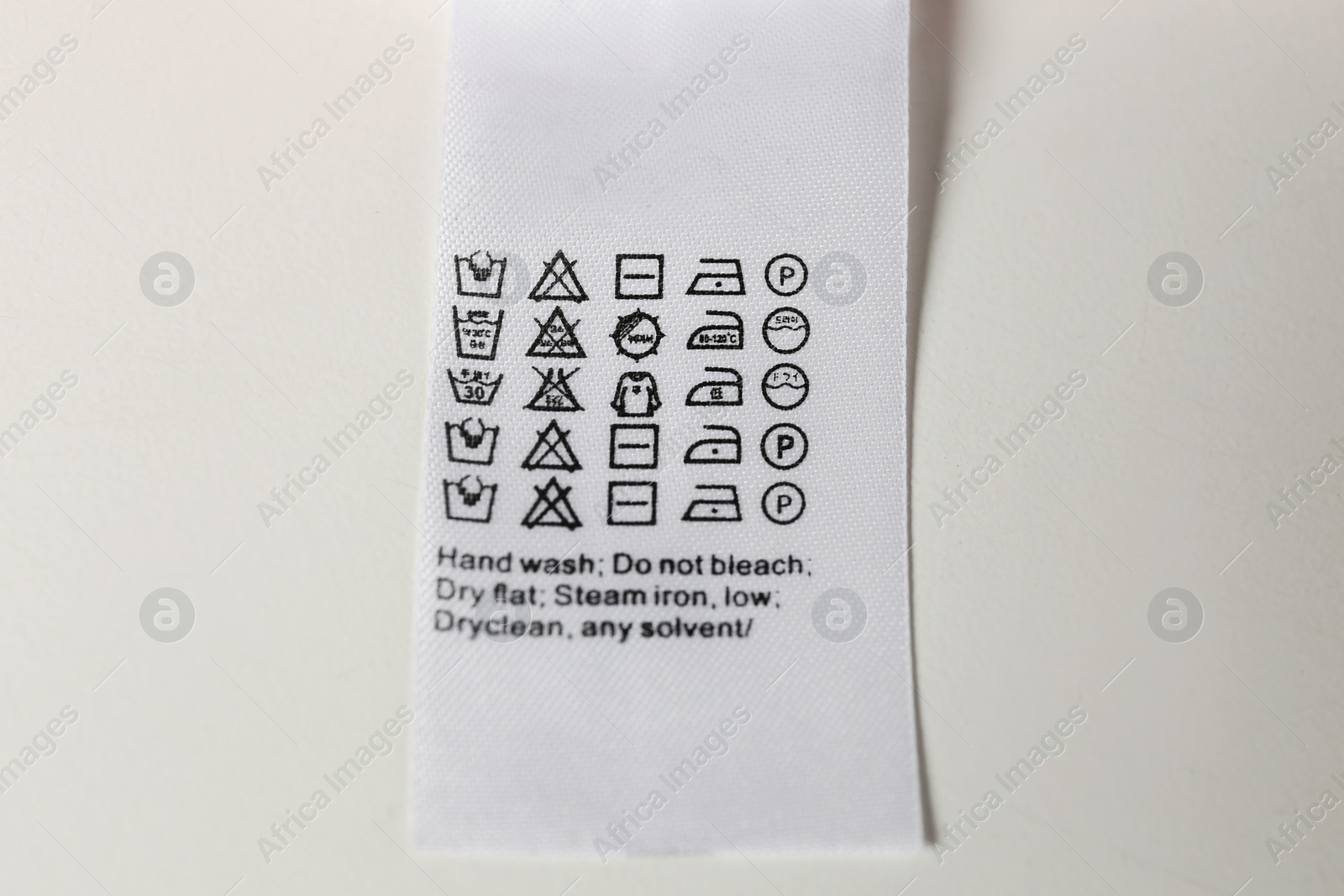 Photo of Clothing label with care symbols on white background, top view