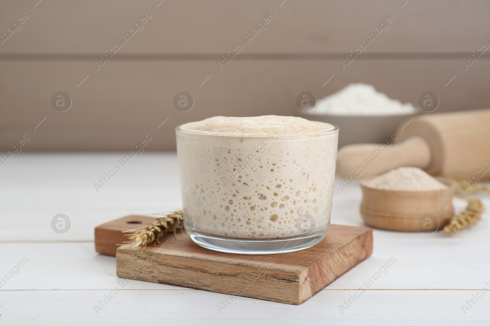 Photo of Leaven and ear of wheat on white wooden table