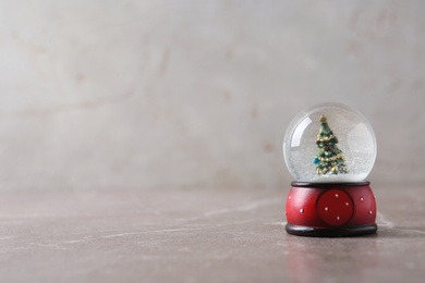 Snow globe with Christmas tree on marble table, space for text