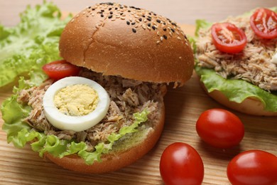 Photo of Delicious sandwiches with tuna, boiled egg and vegetables on wooden table