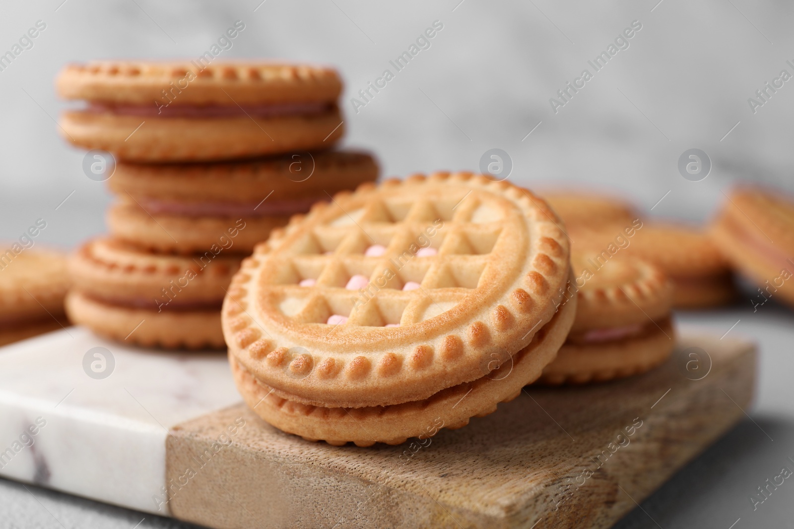 Photo of Tasty sandwich cookies with cream on board, closeup