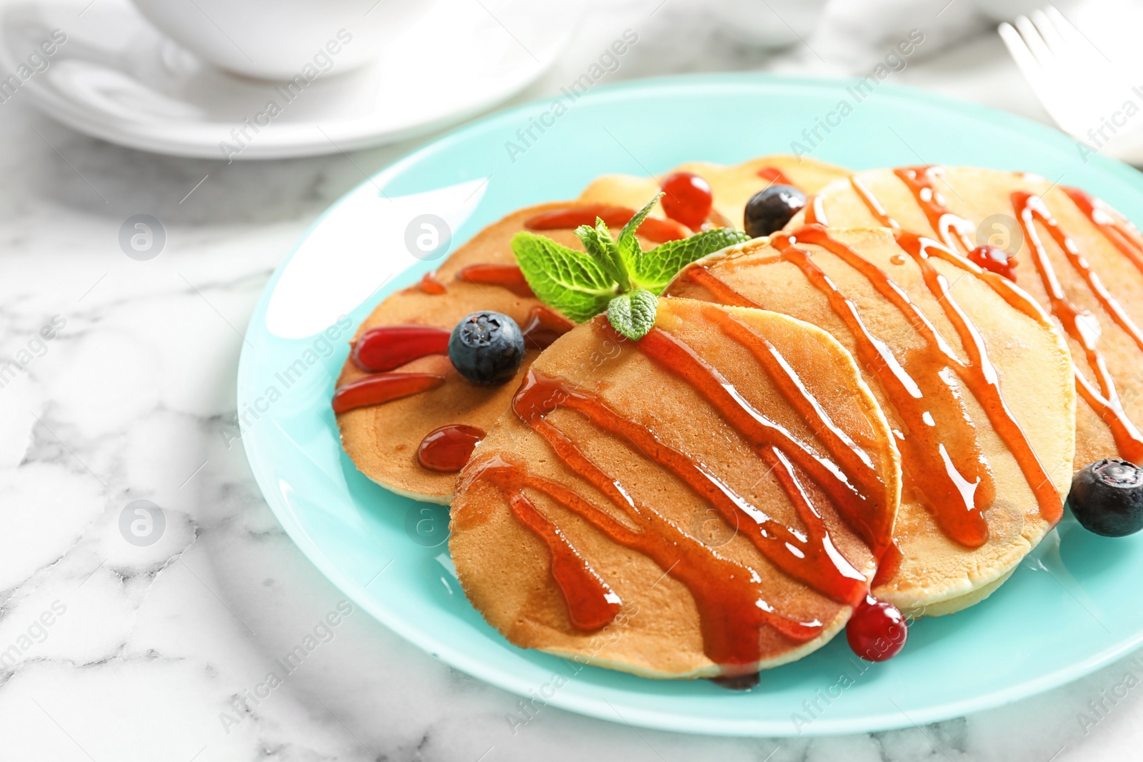 Photo of Tasty pancakes with berries and syrup on table