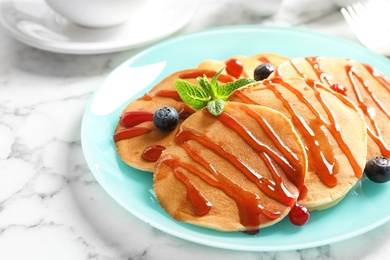 Photo of Tasty pancakes with berries and syrup on table