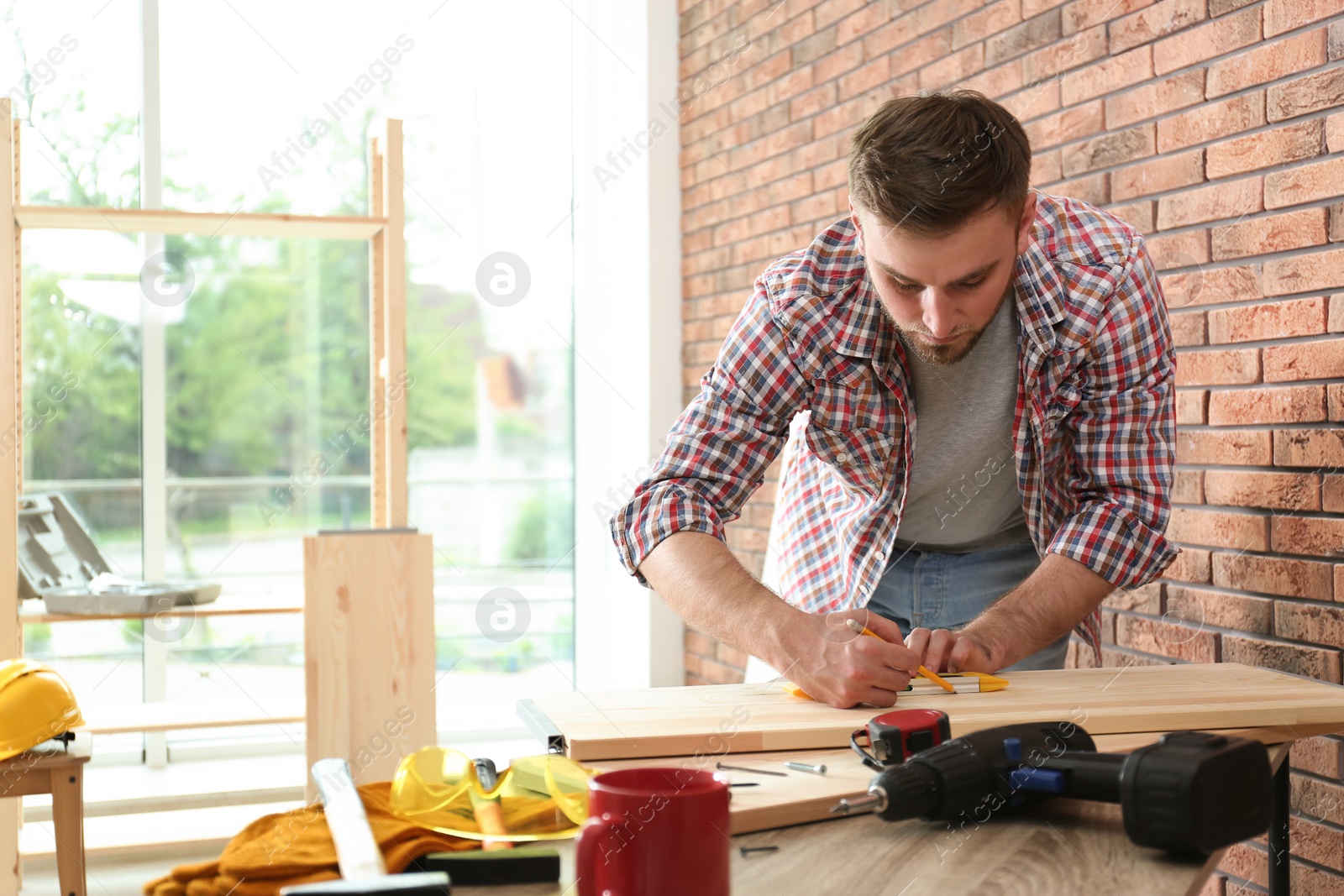 Photo of Young man working near brick wall indoors. Space for text