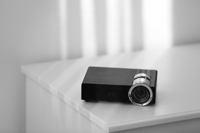 Photo of Modern video projector on white table indoors