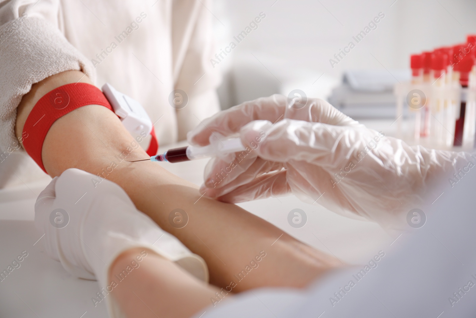 Photo of Nurse drawing blood sample from patient in clinic, closeup