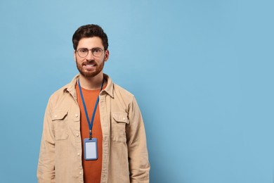 Photo of Smiling man with VIP pass badge on light blue background, space for text
