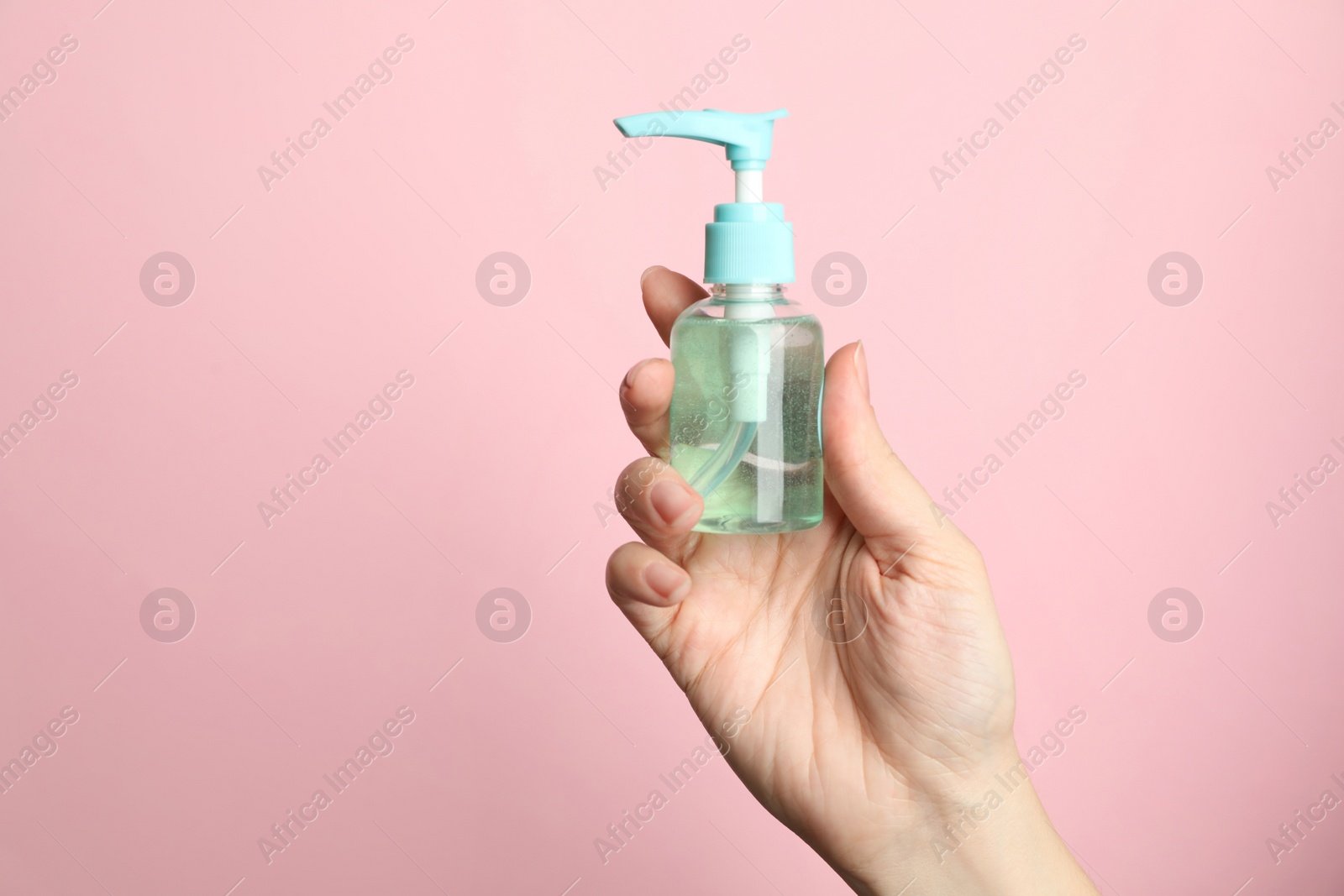 Photo of Woman holding antiseptic gel on pink background, closeup