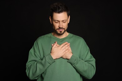 Photo of Man with clasped hands praying on black background