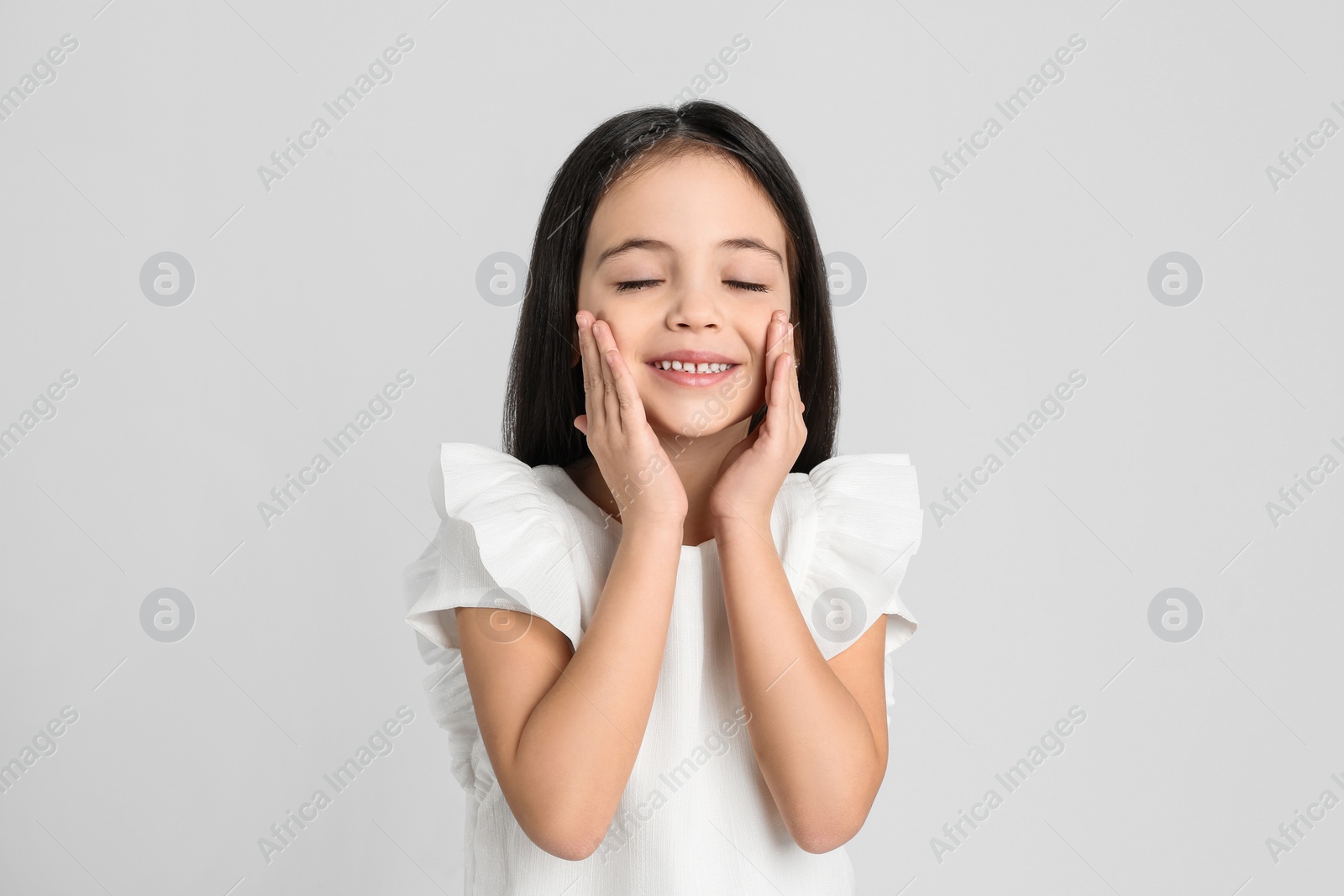 Photo of Portrait of cute little girl on light grey background