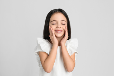 Portrait of cute little girl on light grey background