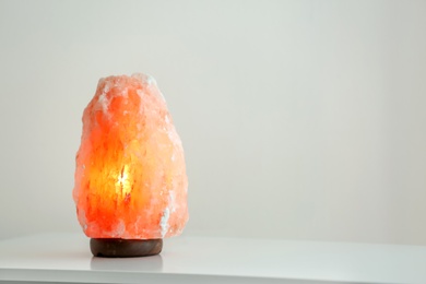 Himalayan salt lamp on table against light background