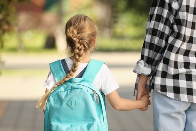 Photo of Little girl with her mother on way to school, back view