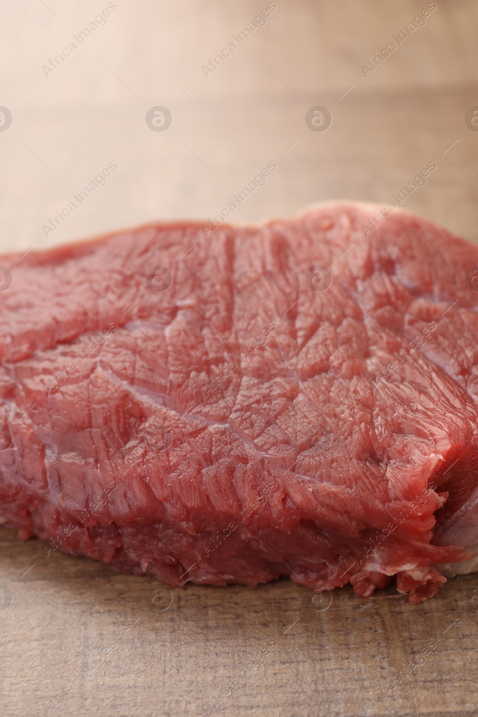 Photo of Piece of raw beef meat on wooden table, closeup