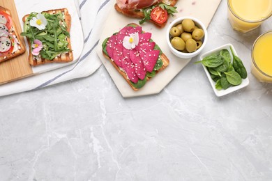 Photo of Different delicious sandwiches on light marble table, flat lay. Space for text